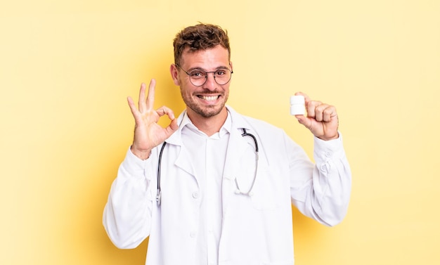 Jovem bonito se sentindo feliz, mostrando aprovação com um gesto certo. conceito de frasco de comprimidos para médico