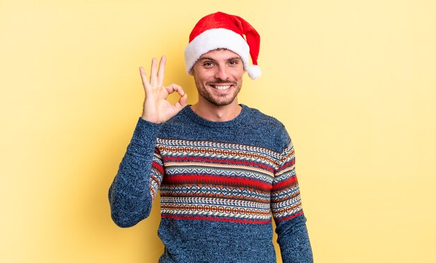 Jovem bonito se sentindo feliz, mostrando aprovação com um gesto certo. conceito de natal