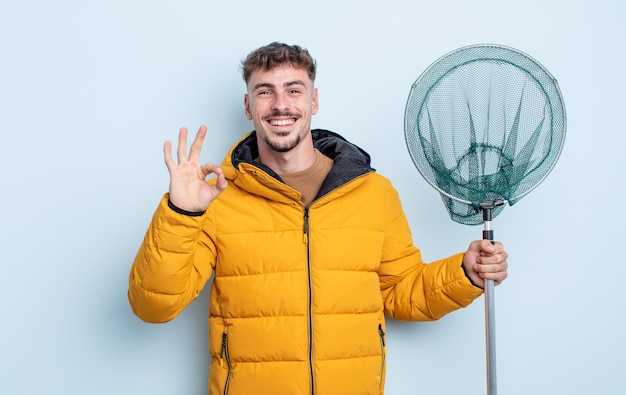 Jovem bonito se sentindo feliz, mostrando aprovação com um gesto certo. conceito de pescador