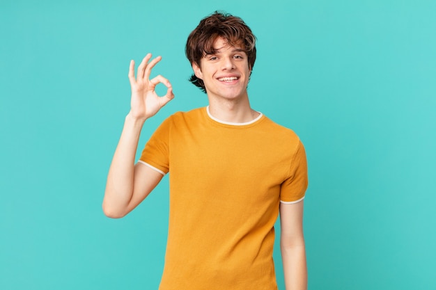 Jovem bonito se sentindo feliz, mostrando aprovação com um gesto de ok