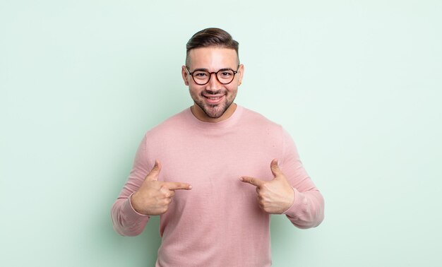 Jovem bonito se sentindo feliz, surpreso e orgulhoso, apontando para si mesmo com um olhar animado e surpreso