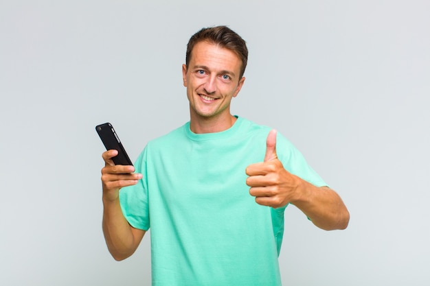 Jovem bonito se sentindo orgulhoso, despreocupado, confiante e feliz, sorrindo positivamente com o polegar para cima