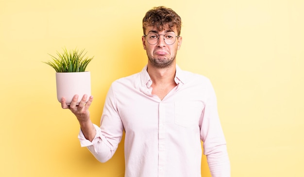 jovem bonito se sentindo triste e choroso com um olhar infeliz e chorando. conceito de planta decorativa