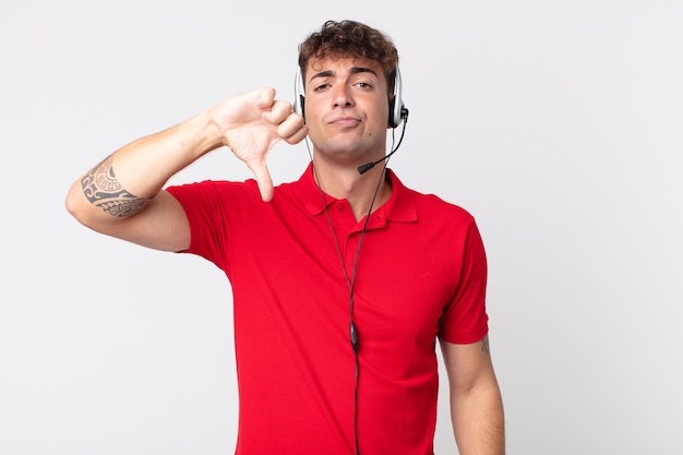 Jovem bonito se sentindo zangado, mostrando os polegares para baixo. conceito de telemarketing