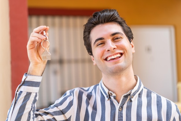 Jovem bonito segurando as chaves de casa com expressão feliz