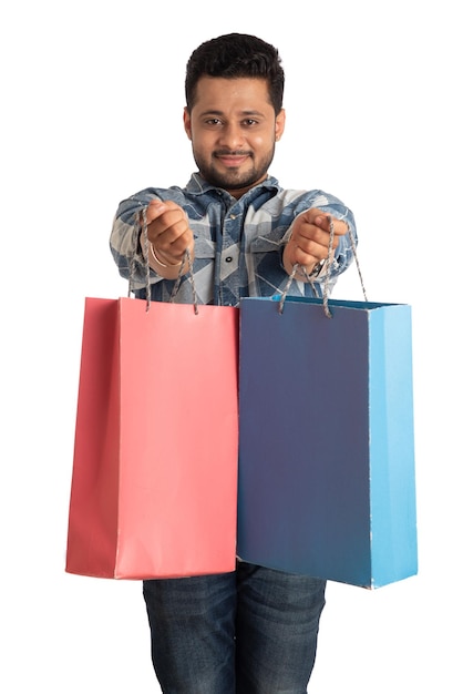 Jovem bonito segurando e posando com sacolas de compras em um fundo branco