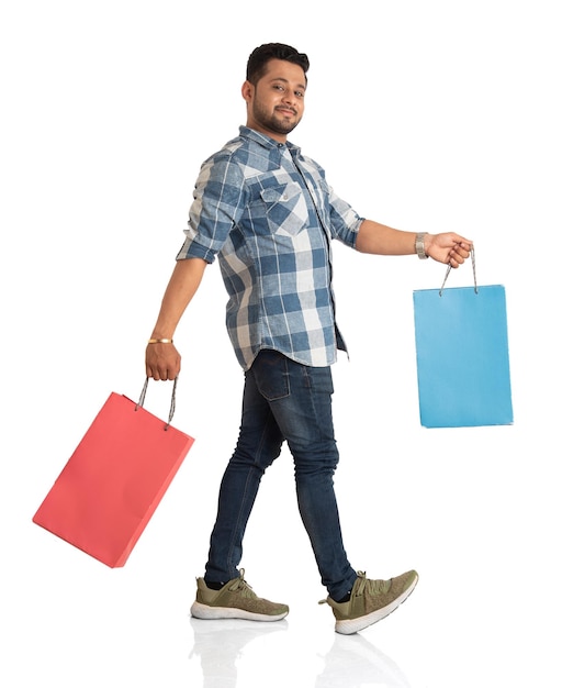 Jovem bonito segurando e posando com sacolas de compras em um fundo branco