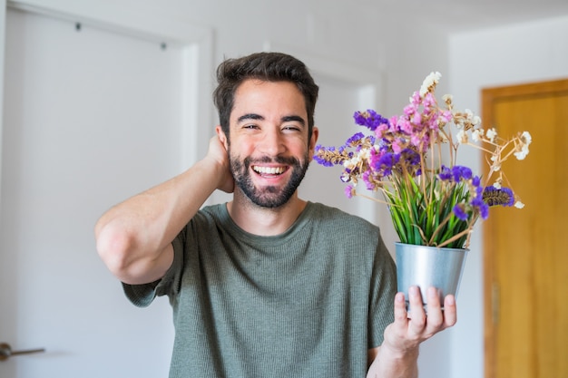 Jovem bonito segurando flores em casa