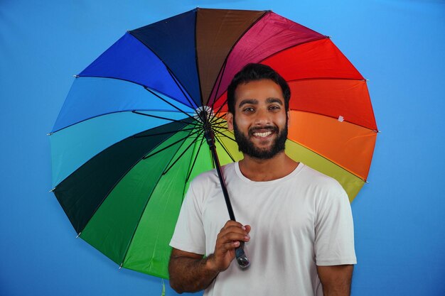 Jovem bonito segurando guarda-chuva colorido e dando expressão espantada, medo e rosto animado