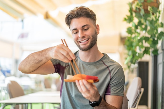 Jovem bonito segurando sashimi ao ar livre