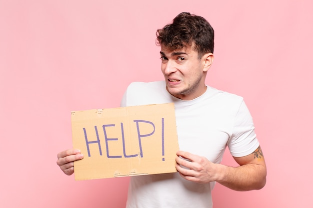 Jovem bonito segurando um cartaz com o texto: AJUDA