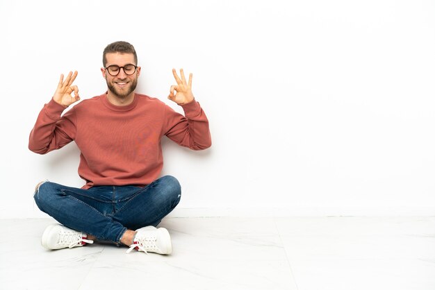 Jovem bonito sentado no chão em pose zen