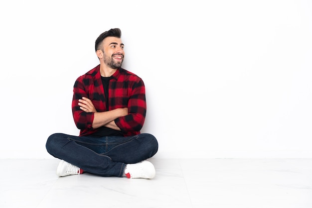 Jovem bonito sentado no chão feliz e sorridente