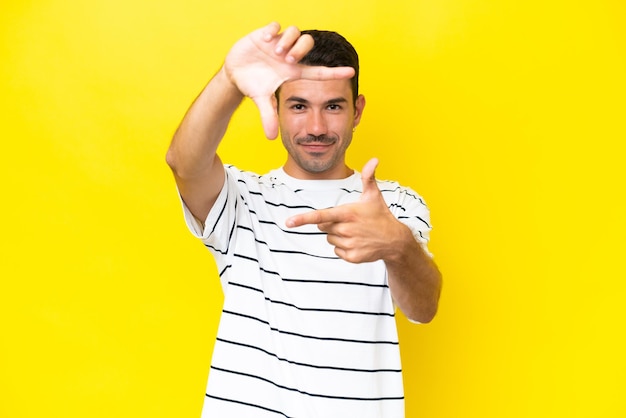 Jovem bonito sobre fundo amarelo isolado focando o rosto Símbolo de enquadramento