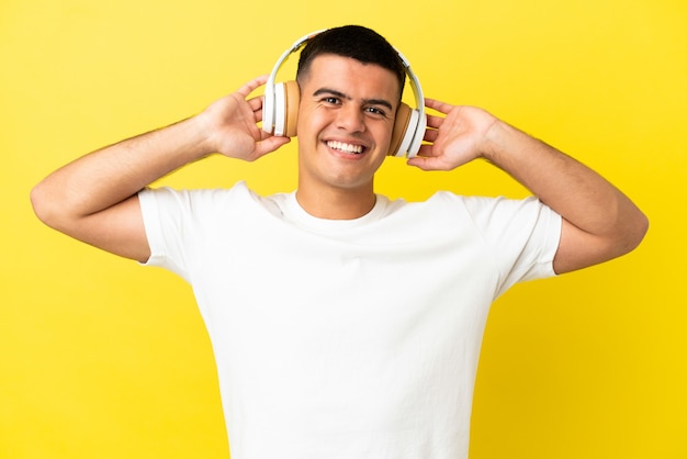 Jovem bonito sobre fundo amarelo isolado ouvindo música