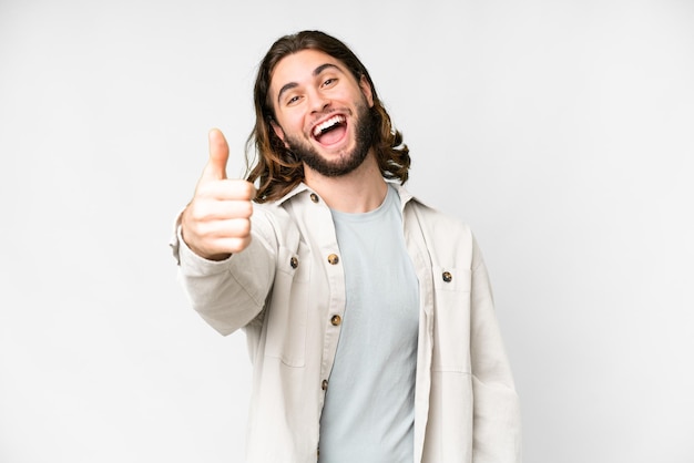 Jovem bonito sobre fundo branco isolado com polegares para cima porque algo de bom aconteceu