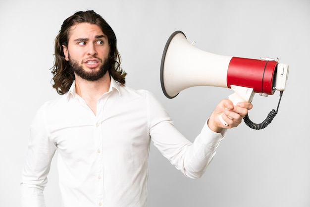 Foto jovem bonito sobre fundo branco isolado, segurando um megafone com expressão estressada