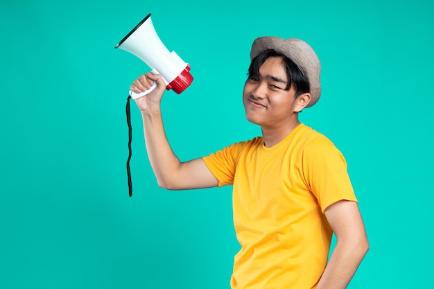 Jovem bonito sobre fundo verde isolado sorrindo através de um megafone