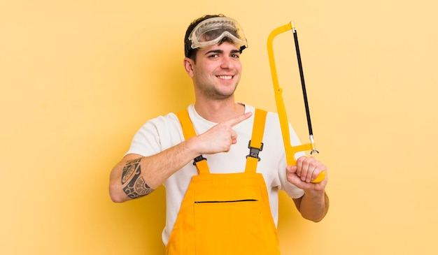 Jovem bonito sorrindo alegremente se sentindo feliz e apontando para o conceito de faz-tudo lateral