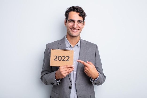 Jovem bonito sorrindo alegremente, sentindo-se feliz e apontando para o lado. conceito de calendário