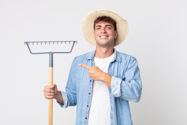 Jovem bonito sorrindo alegremente, sentindo-se feliz e apontando para o lado. conceito de fazendeiro