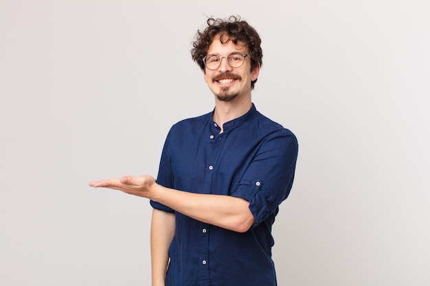 Jovem bonito sorrindo alegremente, sentindo-se feliz e mostrando um conceito