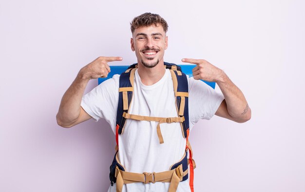 Jovem bonito sorrindo com confiança apontando para próprio sorriso largo. conceito de alpinista