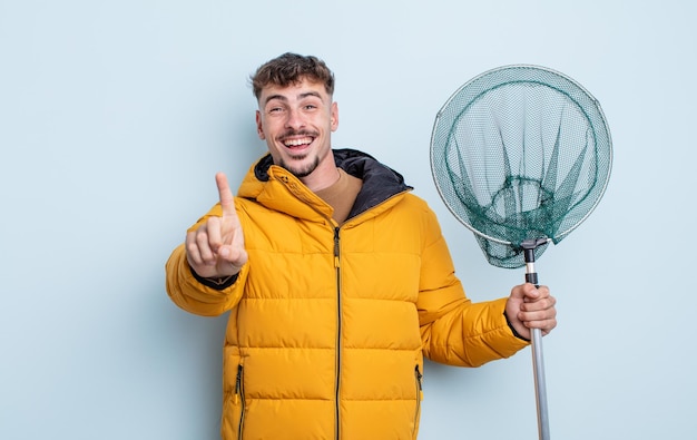 Jovem bonito sorrindo com orgulho e com confiança, fazendo o número um. conceito de pescador