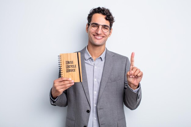 Jovem bonito sorrindo com orgulho e com confiança, fazendo o número um. conceito de reciclagem