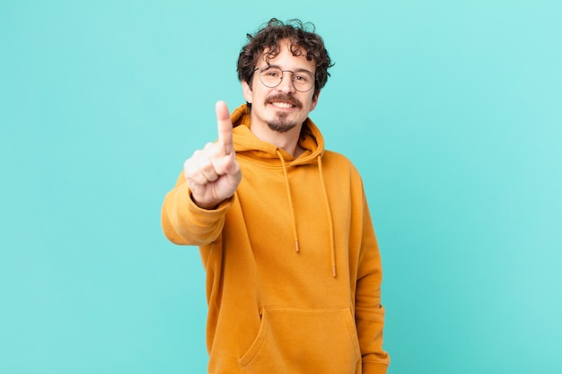 Jovem bonito sorrindo com orgulho e confiança alcançando o primeiro lugar