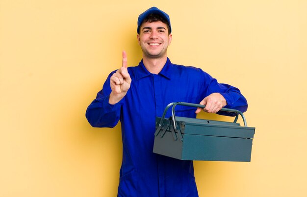 Jovem bonito sorrindo com orgulho e confiança, fazendo o conceito de encanador número um