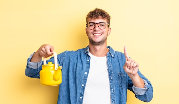 Jovem bonito sorrindo com orgulho e confiança fazendo o conceito número um.