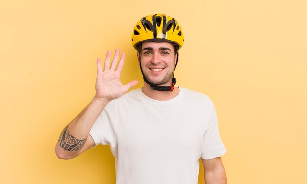 Jovem bonito sorrindo e parecendo amigável mostrando o conceito de bicicleta número cinco