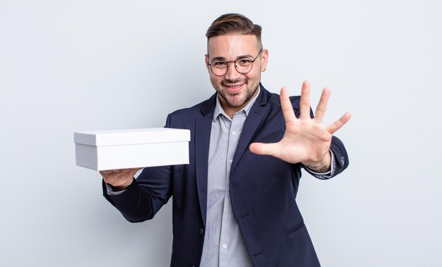 Jovem bonito sorrindo e parecendo amigável, mostrando o conceito de caixa branca número cinco