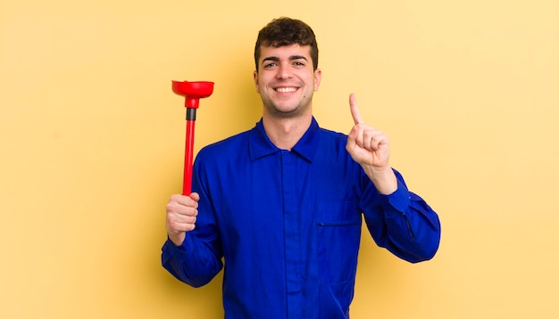 Jovem bonito sorrindo e parecendo amigável, mostrando o conceito de encanador número um