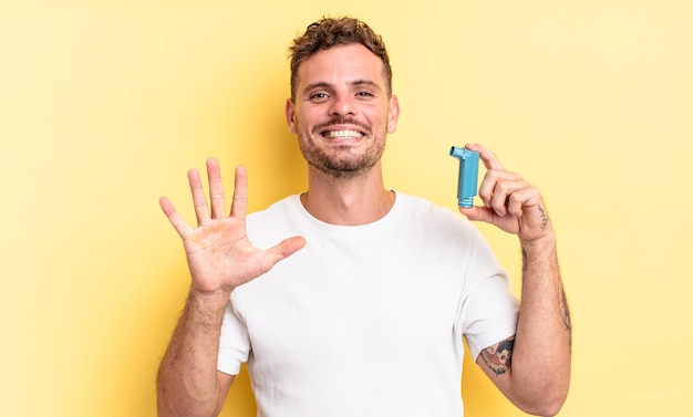 Jovem bonito sorrindo e parecendo amigável, mostrando o número cinco. conceito de asma