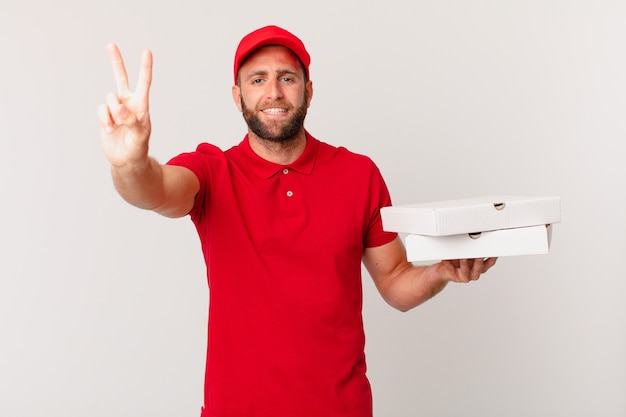 Jovem bonito sorrindo e parecendo amigável, mostrando o número dois. conceito de entrega de pizza