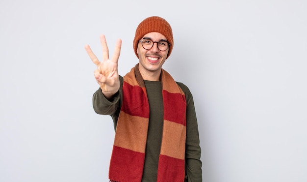 Jovem bonito sorrindo e parecendo amigável, mostrando o número três. conceito de roupas de inverno