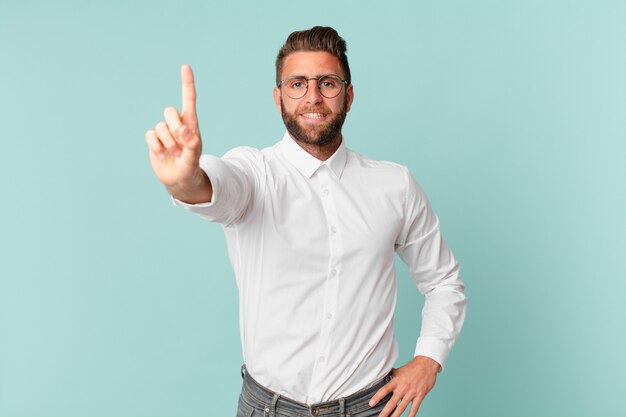 Jovem bonito sorrindo e parecendo amigável, mostrando o número um