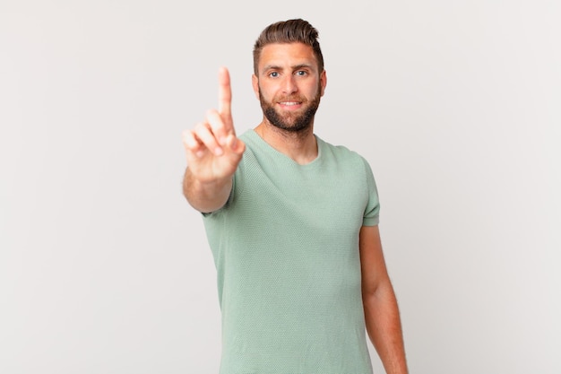 Jovem bonito sorrindo e parecendo amigável mostrando o número um