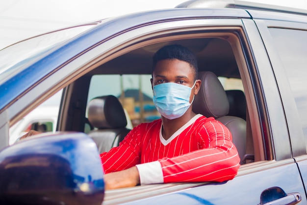 Jovem bonito taxista africano usando máscara facial prevenindo, prevenindo, prevenindo-se do surto na sociedade