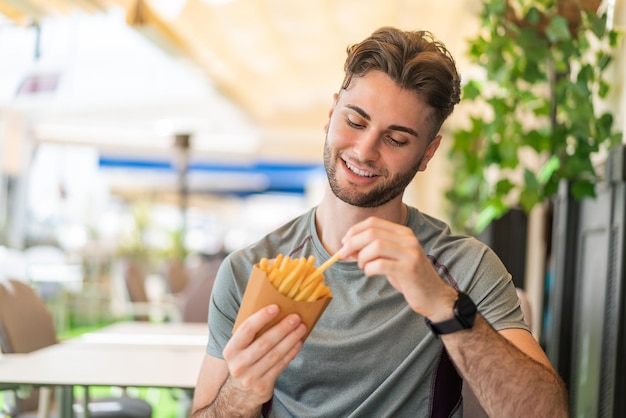 Jovem bonito tomando batatas fritas