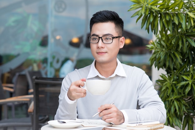 Jovem bonito tomando café na cidade