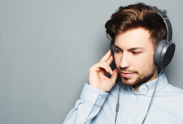 Jovem bonito usando fones de ouvido e ouvir música.