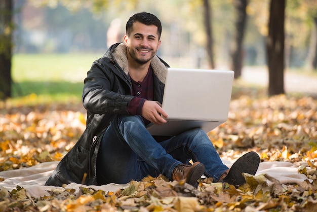 Jovem bonito usando laptop ao ar livre