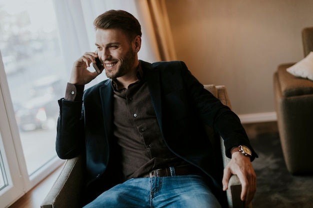 Jovem bonito usando telefone celular no quarto