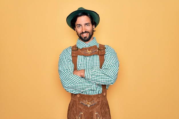 Jovem bonito vestindo tratidional alemão octoberfest custome para o festival da Alemanha rosto feliz sorrindo com os braços cruzados olhando para a câmera Pessoa positiva