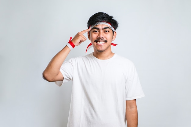 Jovem bonito vestindo uma camisa casual sorrindo apontando para a cabeça com os dedos das duas mãos, ótima ideia ou pensamento, boa memória sobre fundo branco