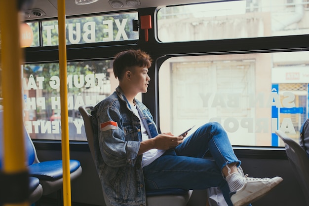 Jovem bonito viajando de ônibus e usando um tablet digital