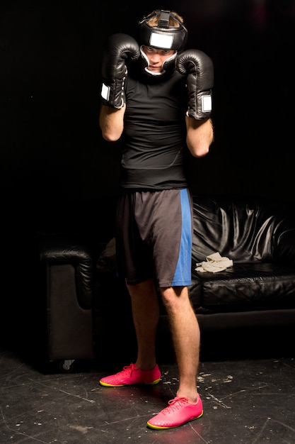 Jovem boxeador em guarda com os punhos enluvados levantados para proteger a cabeça durante um treino de treino